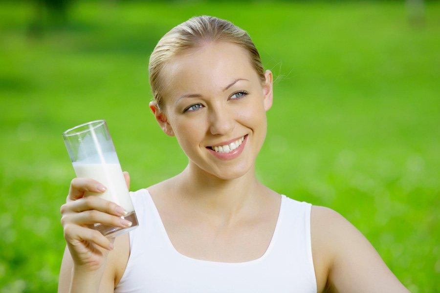 Chica con una botella de kéfir sobre un fondo de hierba verde