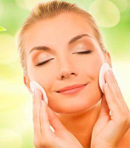 Femme se frotte le visage avec des tampons de coton