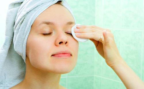 Garota remove maquiagem com uma almofada de algodão