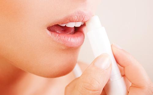 Fille frotte ses lèvres avec du rouge à lèvres hygiénique