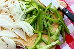 Oignons émincés et poivron vert sur une planche à découper
