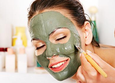 Niña pone una máscara de arcilla en la cara