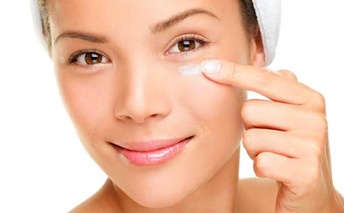 Niña de ojos marrones pone crema hidratante en su dedo