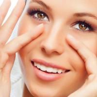 Chica con una sonrisa realiza un simple masaje para los ojos.