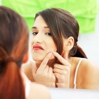 La niña frente al espejo aplasta violentamente un grano