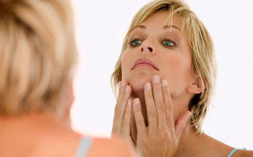 Femme examine son visage.