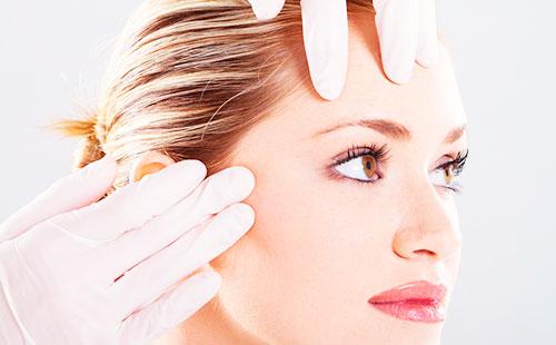 Manos enguantadas en la frente