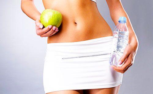 Manzana y botella de agua en manos