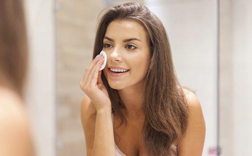 Fille aux cheveux noirs efface le maquillage avec un coton