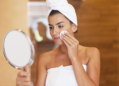 אישה מסתכלת במראה ומשפשפת את פניה