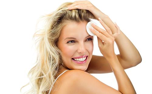 Krásná blondýna si tře čelo bavlněnou podložkou