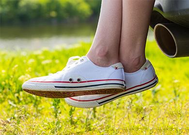 Mga puting sneaker sa mga binti