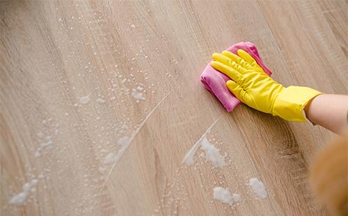 Ang isang gloved na kamay ay naghuhugas ng isang nakalamina na may basahan