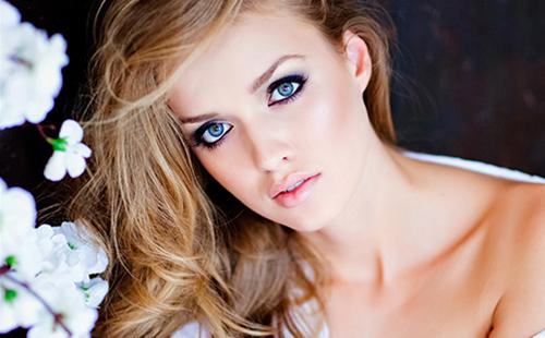 Blonda cu ochi albaștri într-o bluză albă