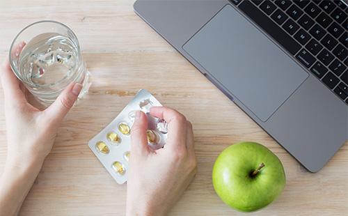 Verre avec de l'eau et des pilules dans les mains.