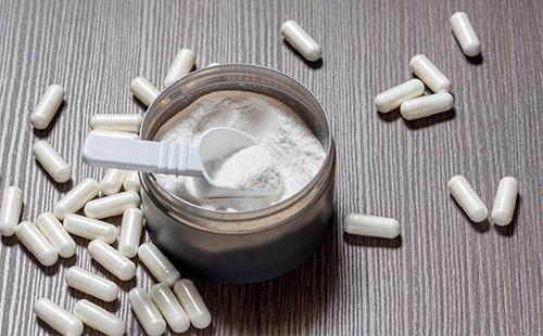 Des pilules blanches sur la table et de la poudre nue dans un bocal