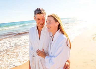 Maligayang mag-asawa sa bathrobes sa tabi ng dagat