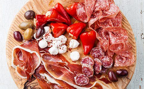 Șuncă și ardei așezate pe o scândură