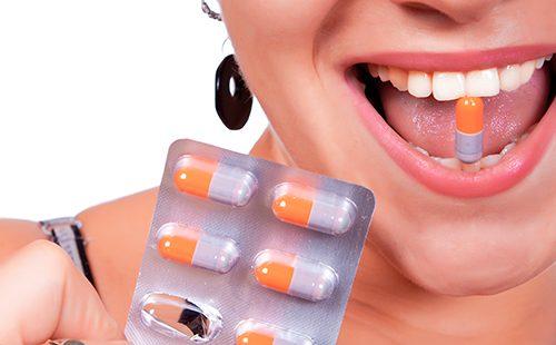 Niña con una sonrisa sostiene una cápsula en los dientes