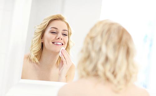 La mujer se limpia la cara con un algodón