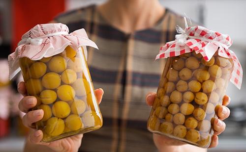 Compote de prunes dans des banques entre les mains d'une femme