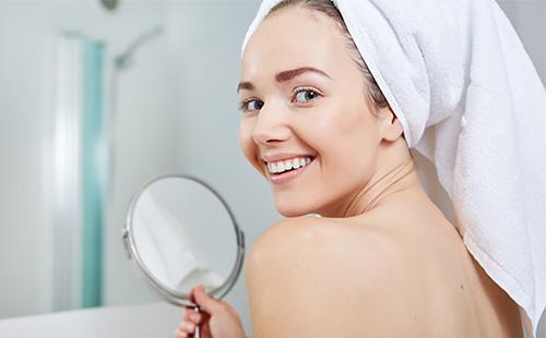 Femme tient un miroir et sourit