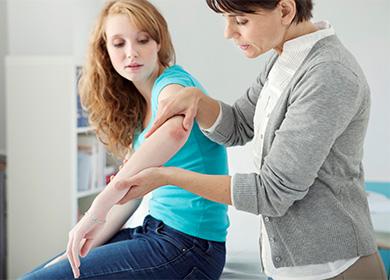 El médico mira el codo del paciente.