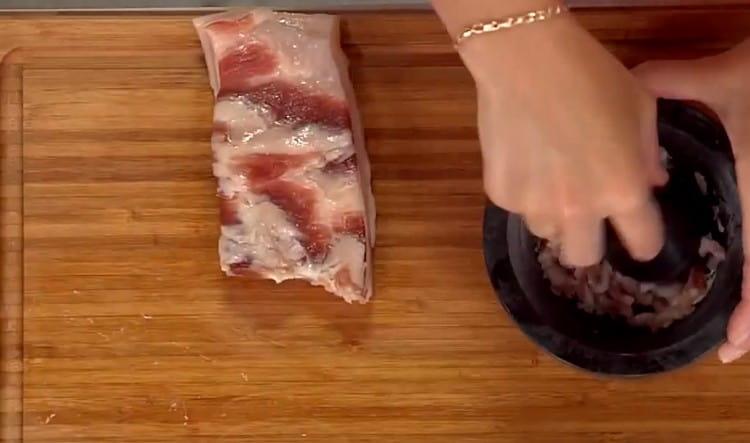 Se macină untura și se toacă usturoiul într-un mortar.