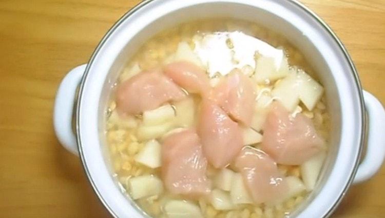 Adăugați puiul și cartofii la mazăre. se toarnă apă și se pune la gătit.