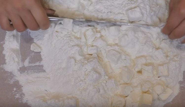 Amb un ganivet, trossegeu la mantega i la farina en molles petites.