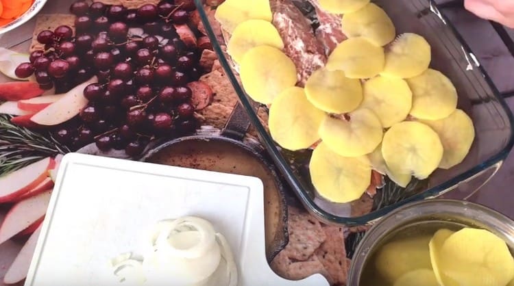 Отгоре на рибата разстиламе нарязаните на тънки кръгчета картофи.