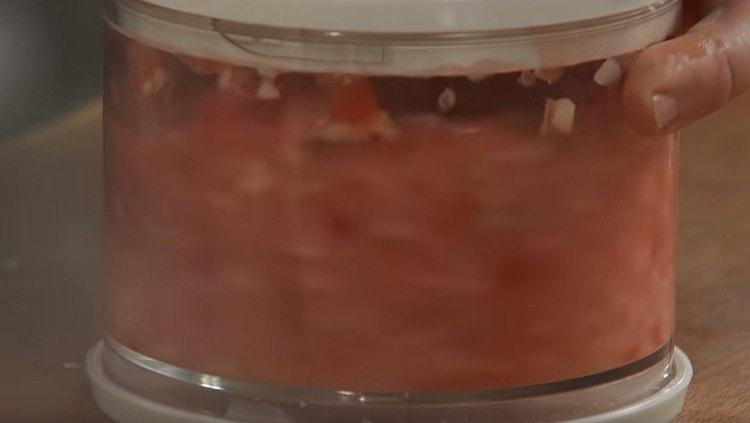 broyer l'ail avec le poivron et les tomates en préparant une sorte d'adjika.