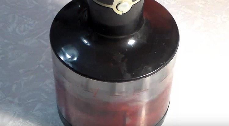 Wir unterbrechen Obst mit Beeren mit einem Mixer.