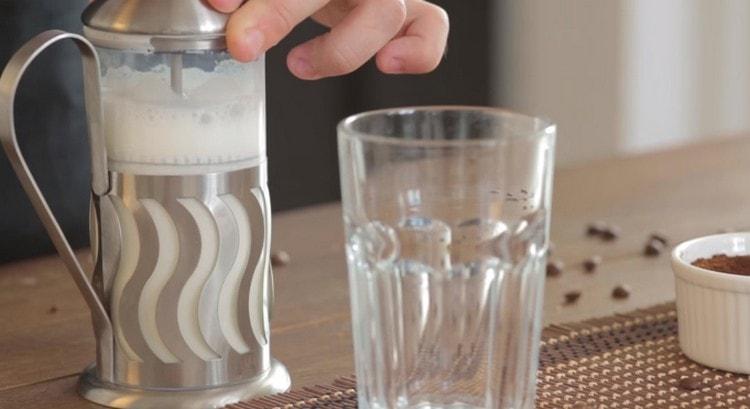 Turnați lapte fierbinte într-o presă franceză și bateți spuma.