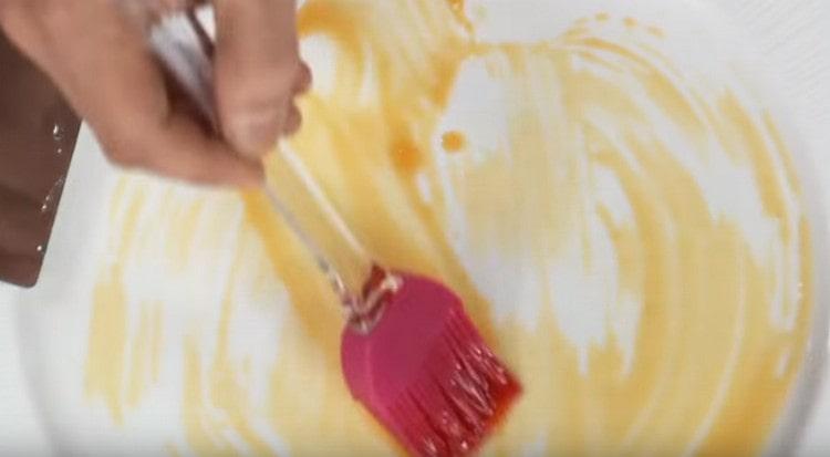 Fetten Sie mit einer Bürste einen Teller mit einer Mischung aus Ölen ein, um das Gericht zu servieren.