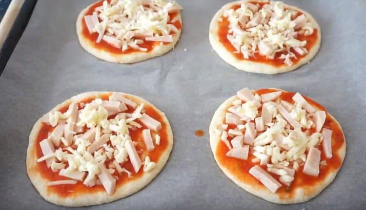 Întindeți șunca și brânza pe fiecare mini pizza.