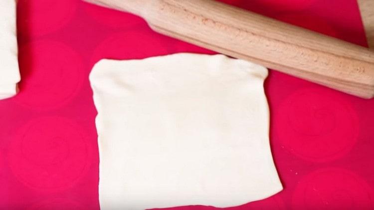 Foaia de patiserie de puf se taie în 4 bucăți și se rulează subțire.