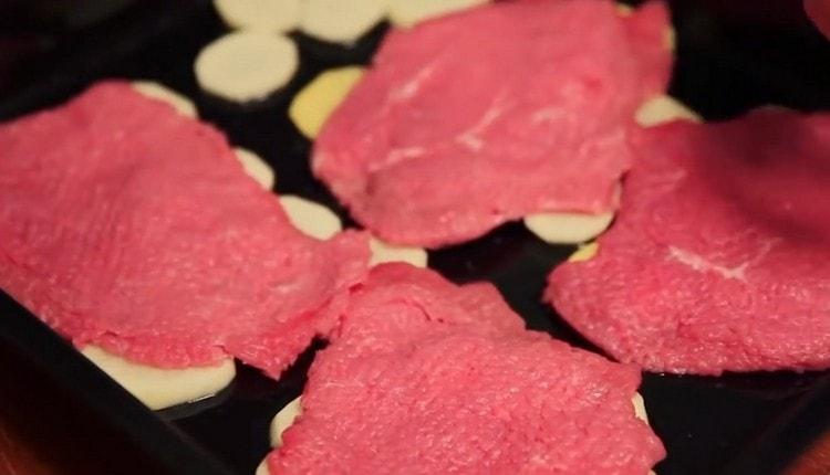 Отгоре на картофите нареждаме пребитото месо.