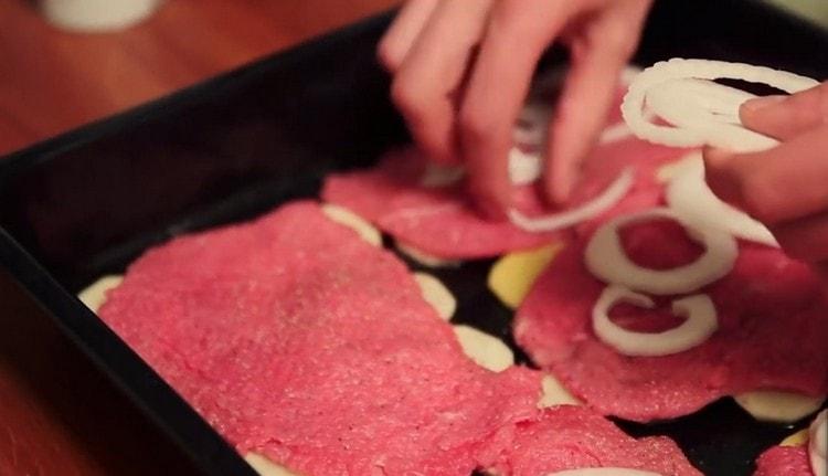 Като пипер и сол месото, ние поставяме пръстени лук върху него.