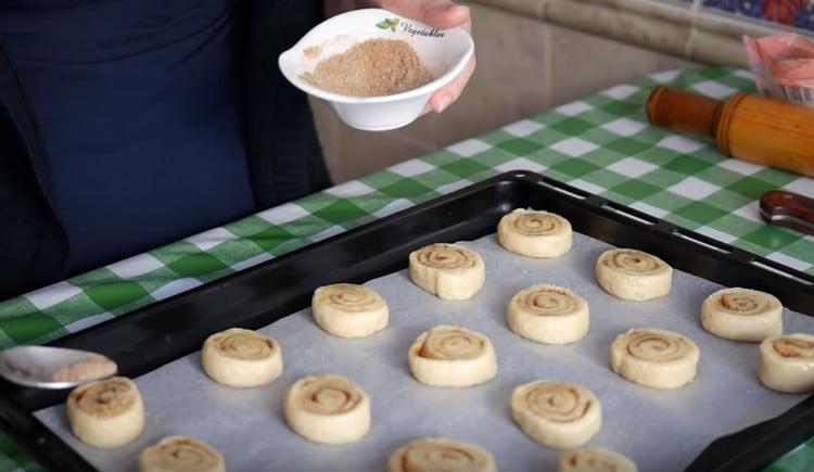 După ce așezați golurile pe o foaie de copt acoperită cu pergament, ungeți-le din nou cu ulei și presărați cu zahăr și scorțișoară.