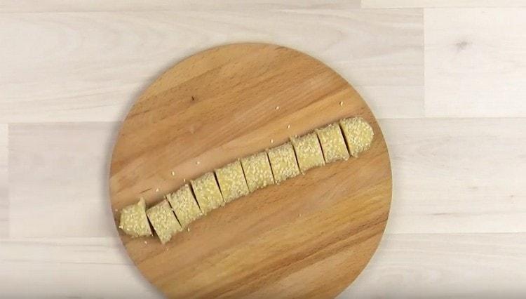 Rotiți cârnații de aluat în susan cu zahăr și tăiați-l în bucăți.