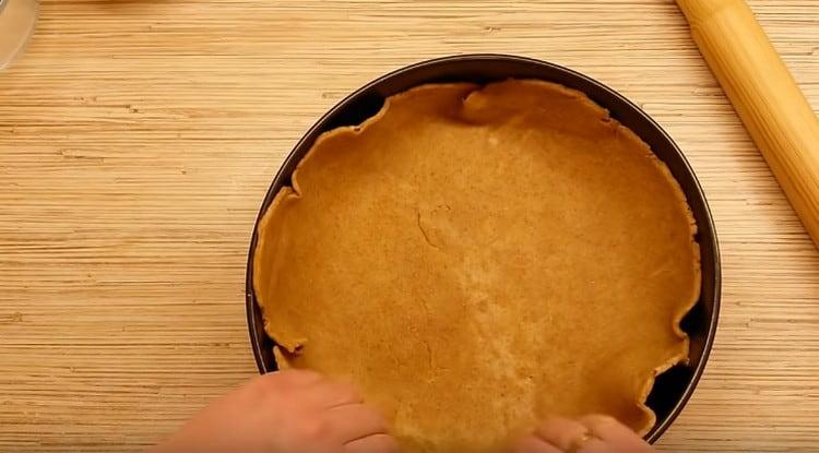 Mudamos a massa para a forma, imediatamente fazemos lados razoavelmente altos.