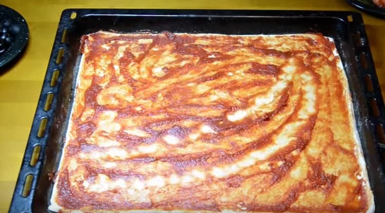 Unte a base da pizza com molho de tomate.