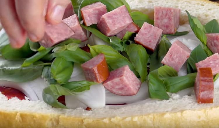 Vi spreder et lag med røget pølser, der er skåret i stykker.