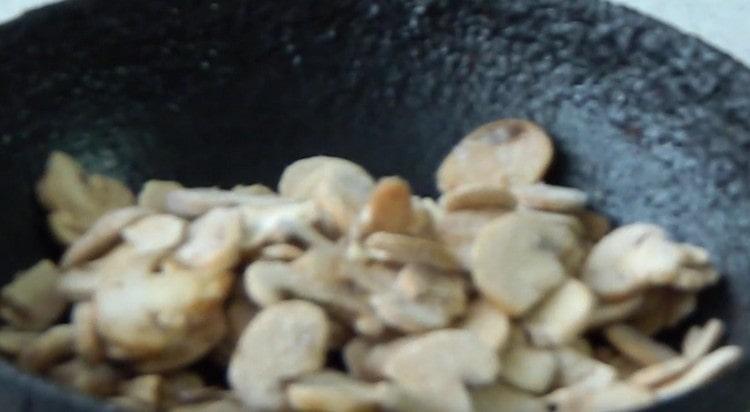 Cogumelos cortados em fatias e frite em uma panela.