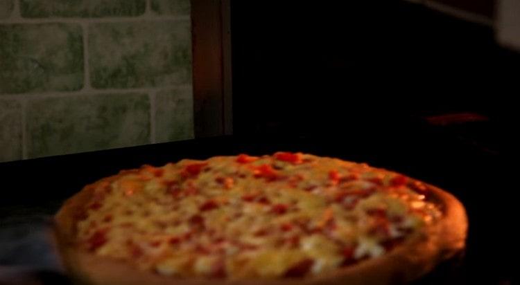 Trimitem pizza la cuptor și coacem până când părțile se rumenesc ușor.