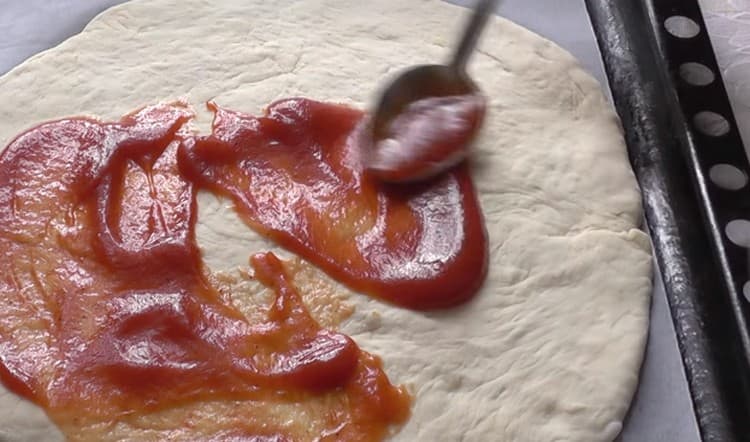 Engrase la base de la pizza con salsa de tomate.