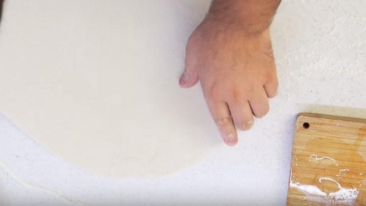 Cu mâinile întindem aluatul pe o suprafață pudră.