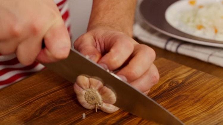 Retirem només la pell de l'all i tallem el fons.