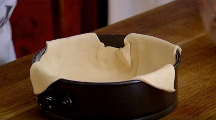 Kami menyebarkan doh ke dalam bentuk sehingga tepi gantung sedikit.